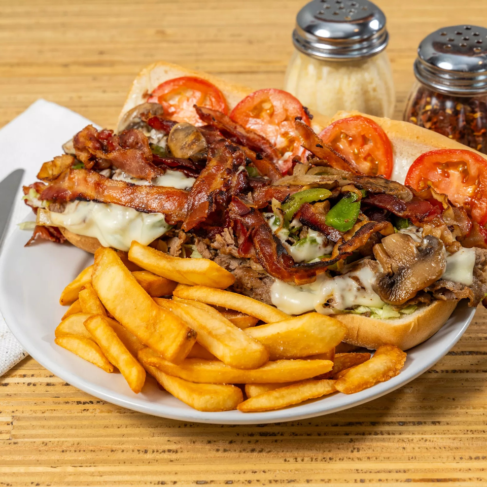 A Bear Brick Oven Co. steak and cheese sub with bacon, mushrooms, and tomatoes, served with fries.